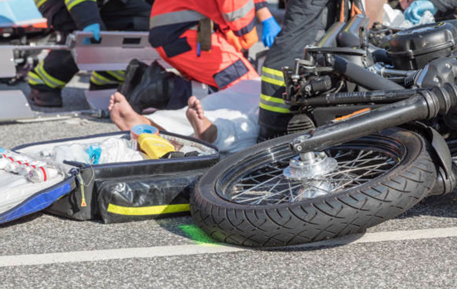 A person is laying on the ground next to a motorcycle.