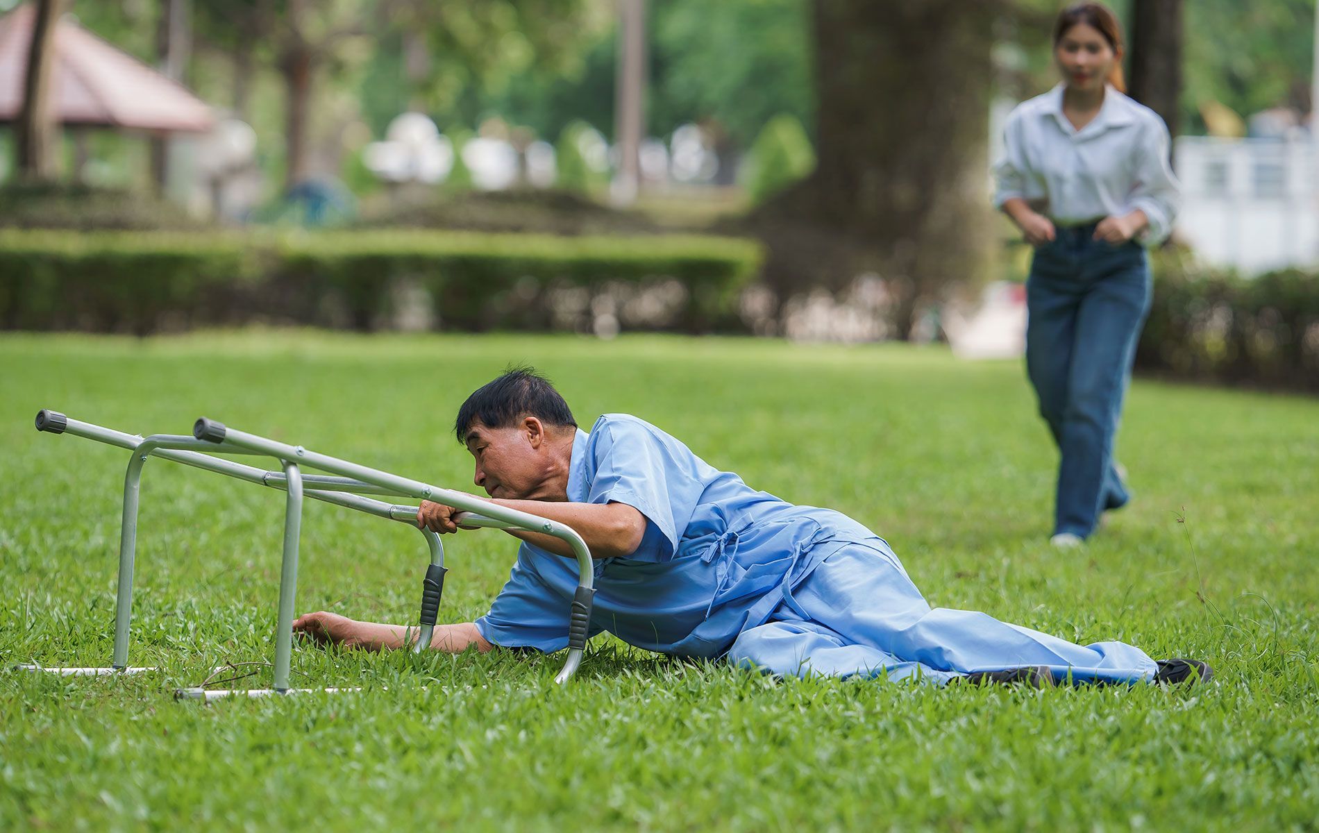 A man is laying on the grass with a walker.