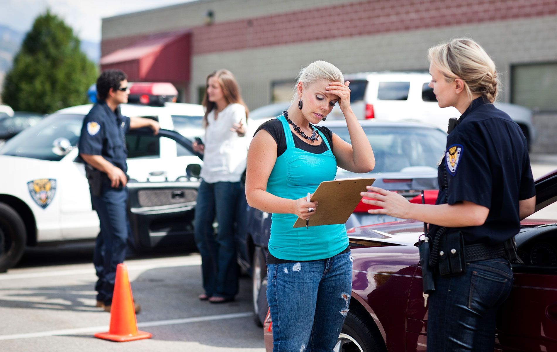 A woman is talking to a police officer while standing next to a car.