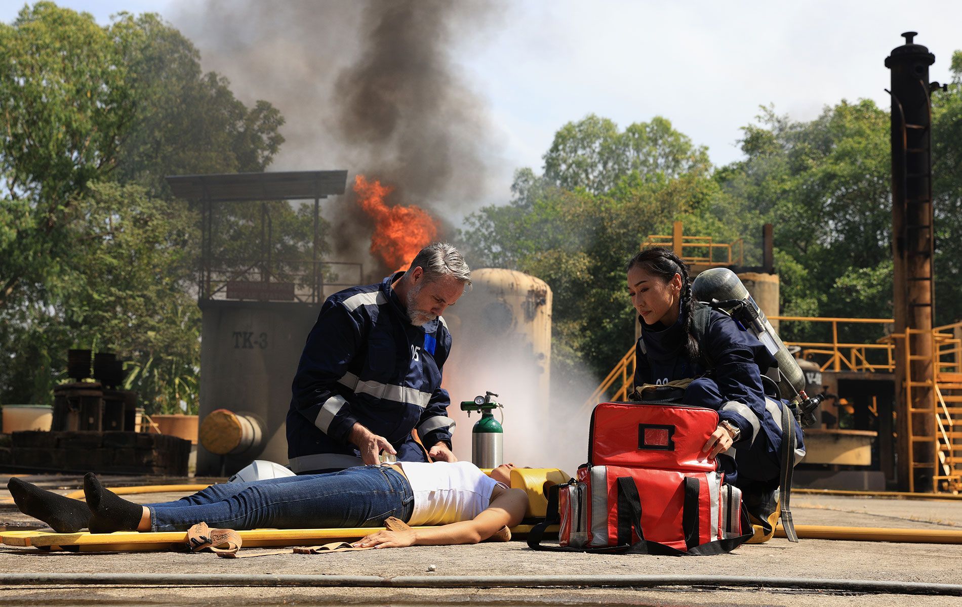 A woman is laying on the ground with a fire in the background.