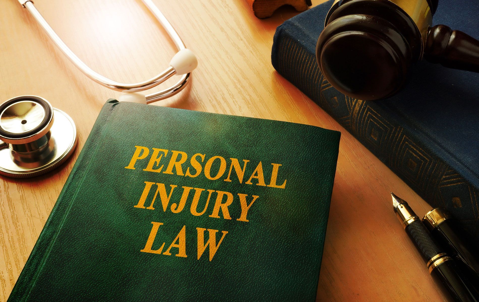 A book titled personal injury law sits on a table next to a stethoscope and a pen