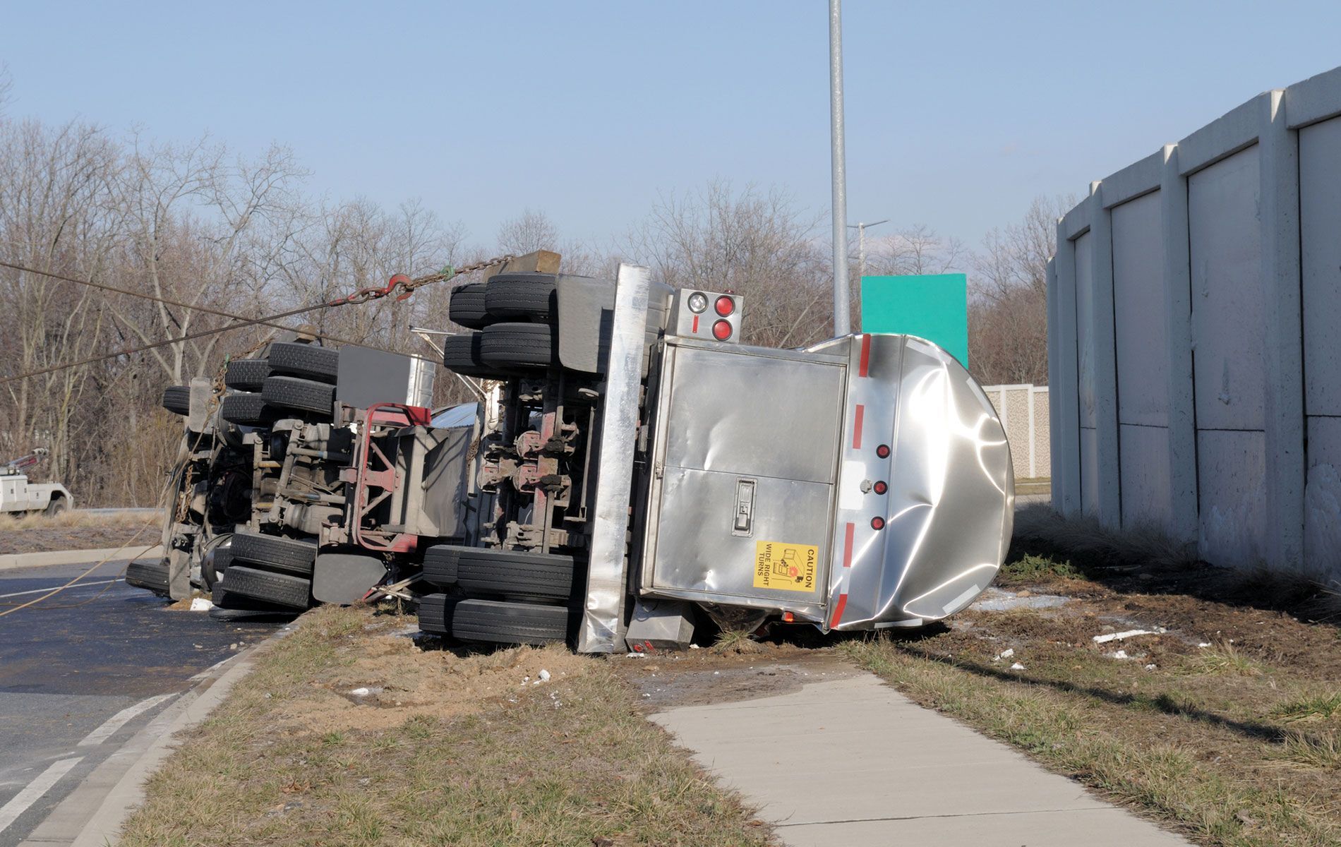 A truck is turned over on its side on the side of the road