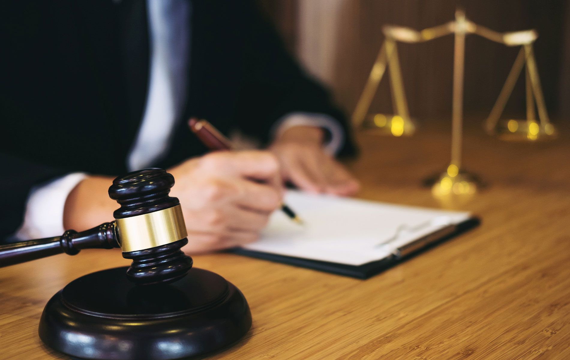 A judge is writing on a clipboard next to a gavel.