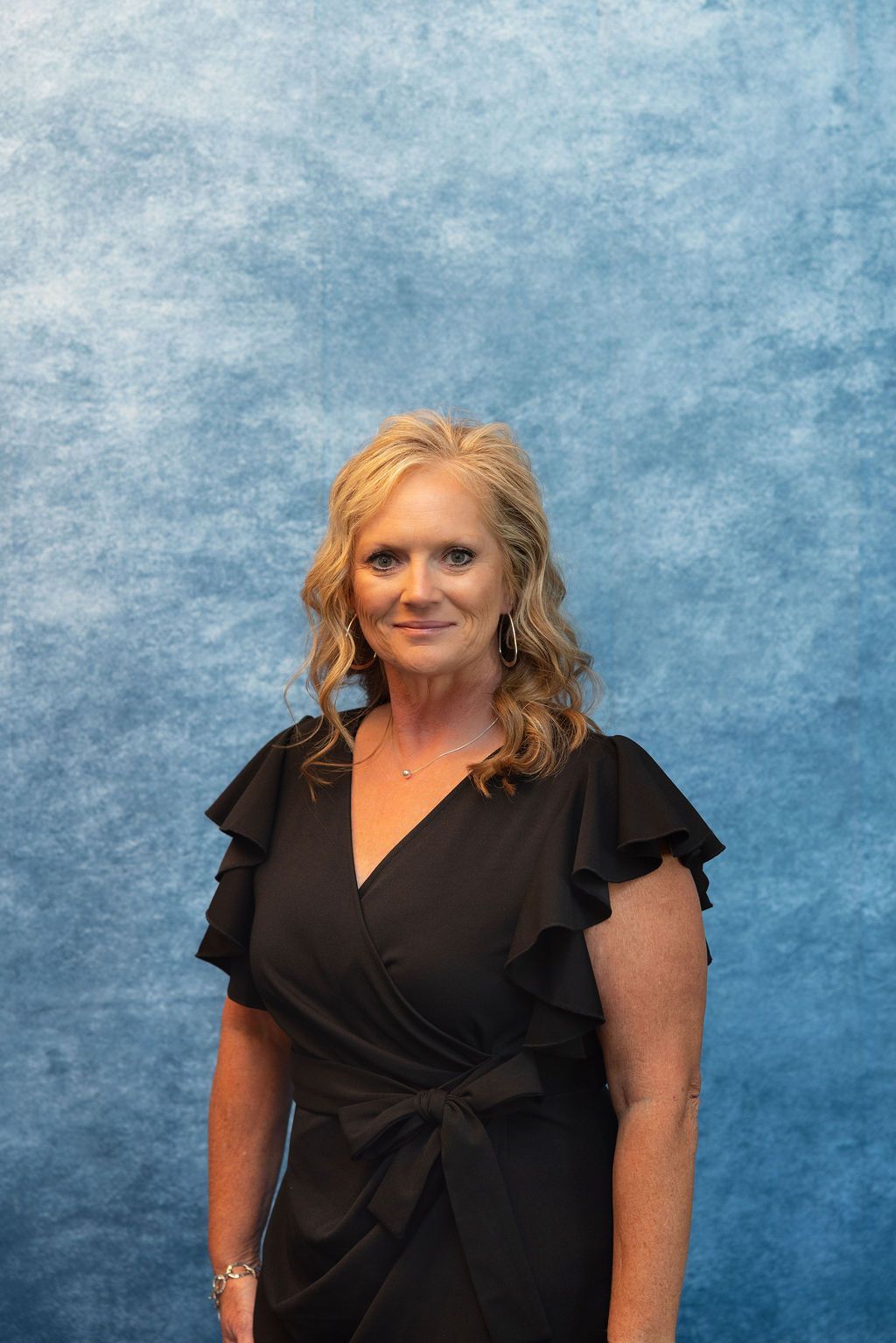 a woman in a white polka dot shirt is smiling for the camera .