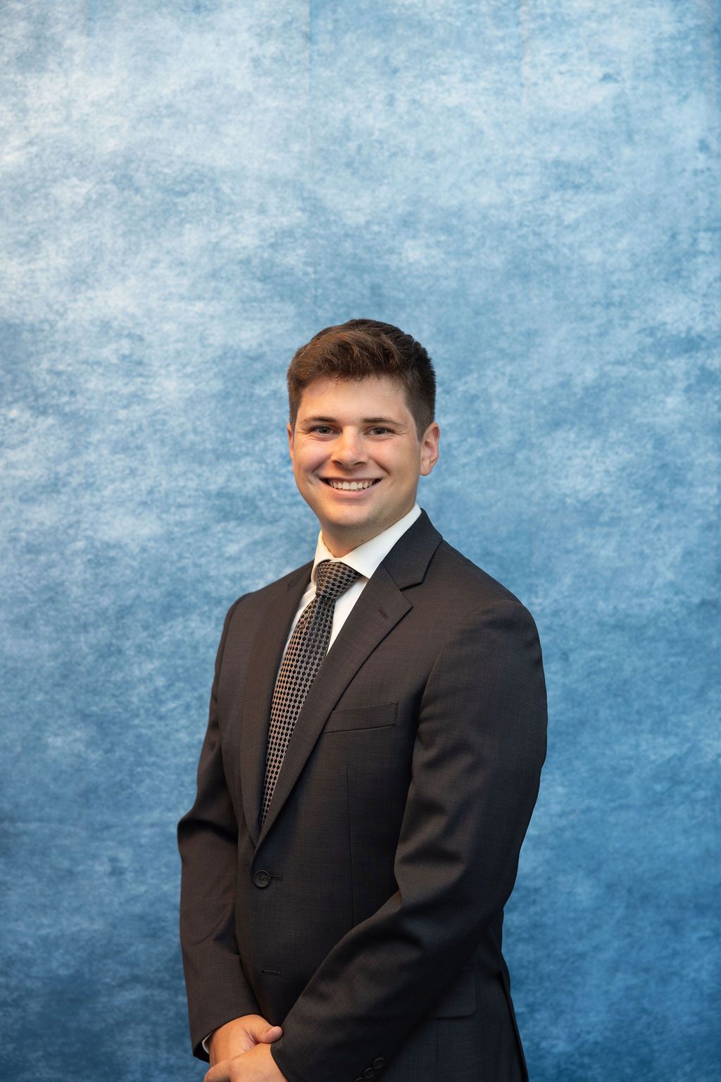 a young man in a suit and tie is smiling for the camera .