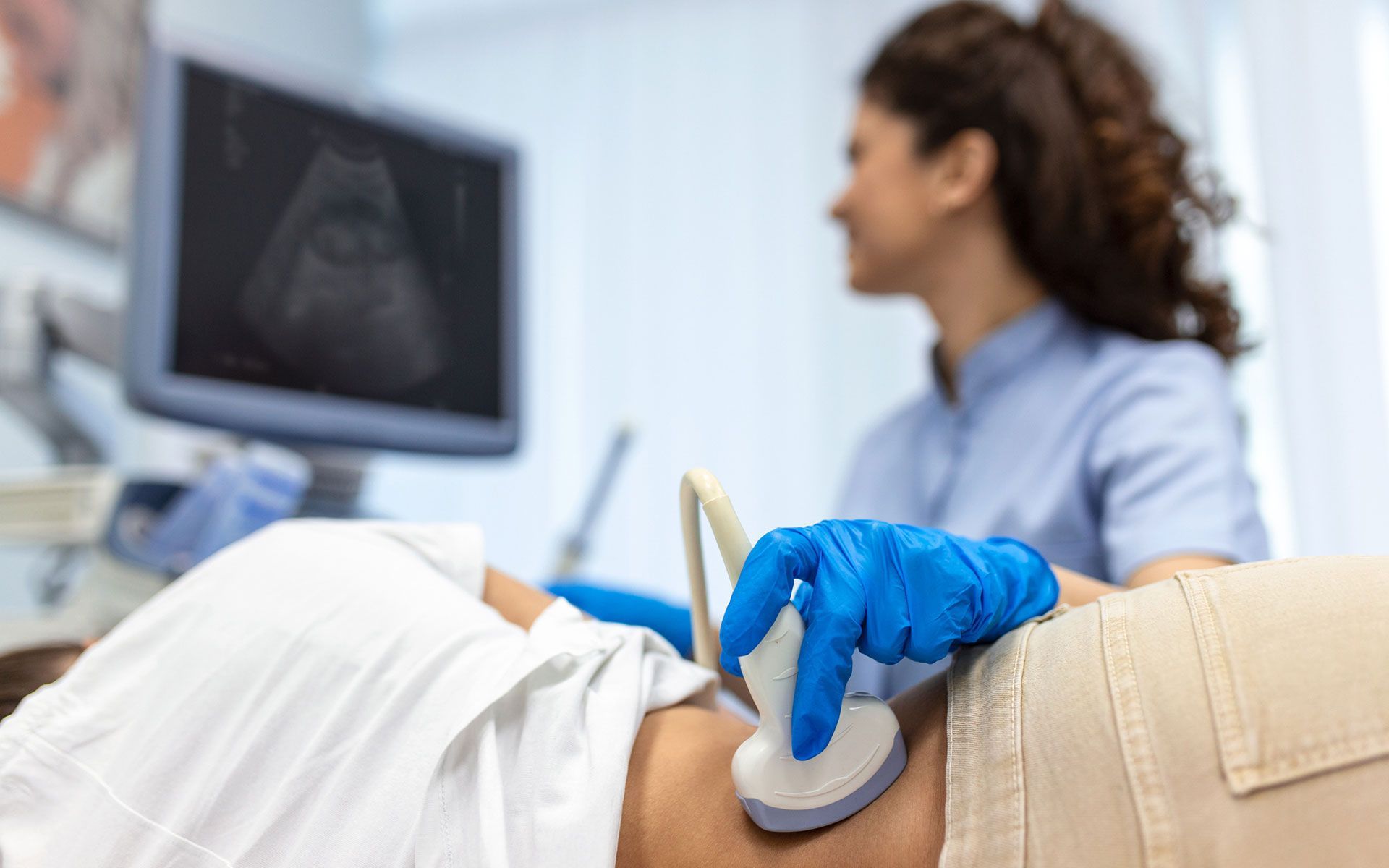 A pregnant woman is getting an ultrasound from a doctor.