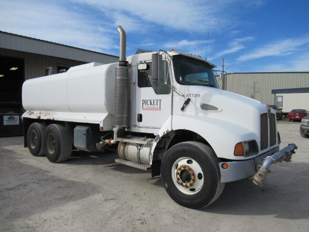 White water tanker truck parked outside a building on a sunny day.
