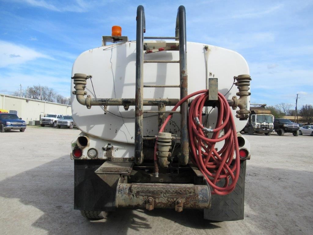 Rear view of a white water truck with a ladder, hose, and warning light.