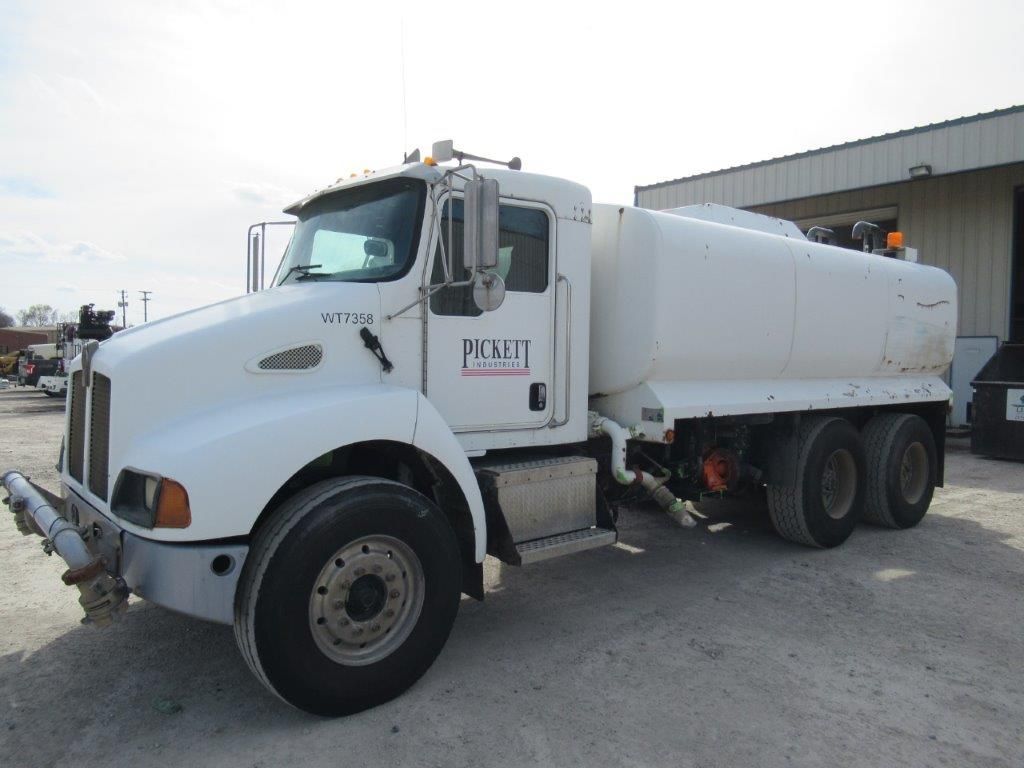 White water tanker truck parked outside a building, sunny day.