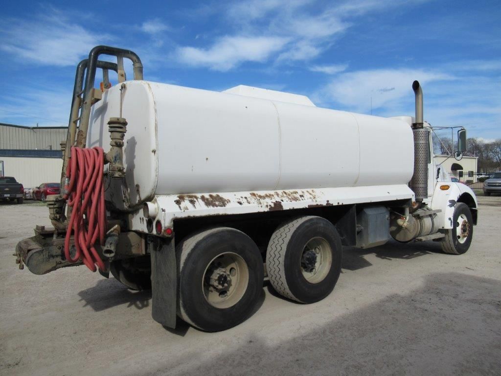 White tanker truck parked outside. Ladder and hose visible.