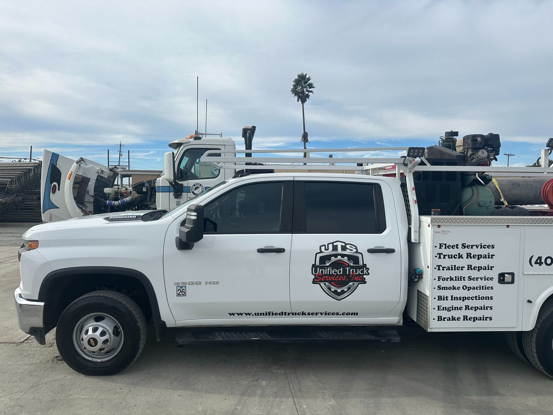 A white truck with a utility bed is parked in a parking lot.