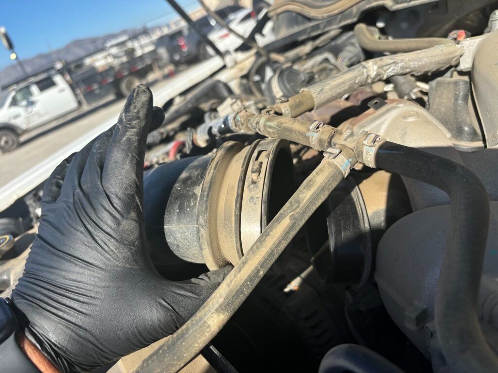 A person wearing black gloves is working on a car engine