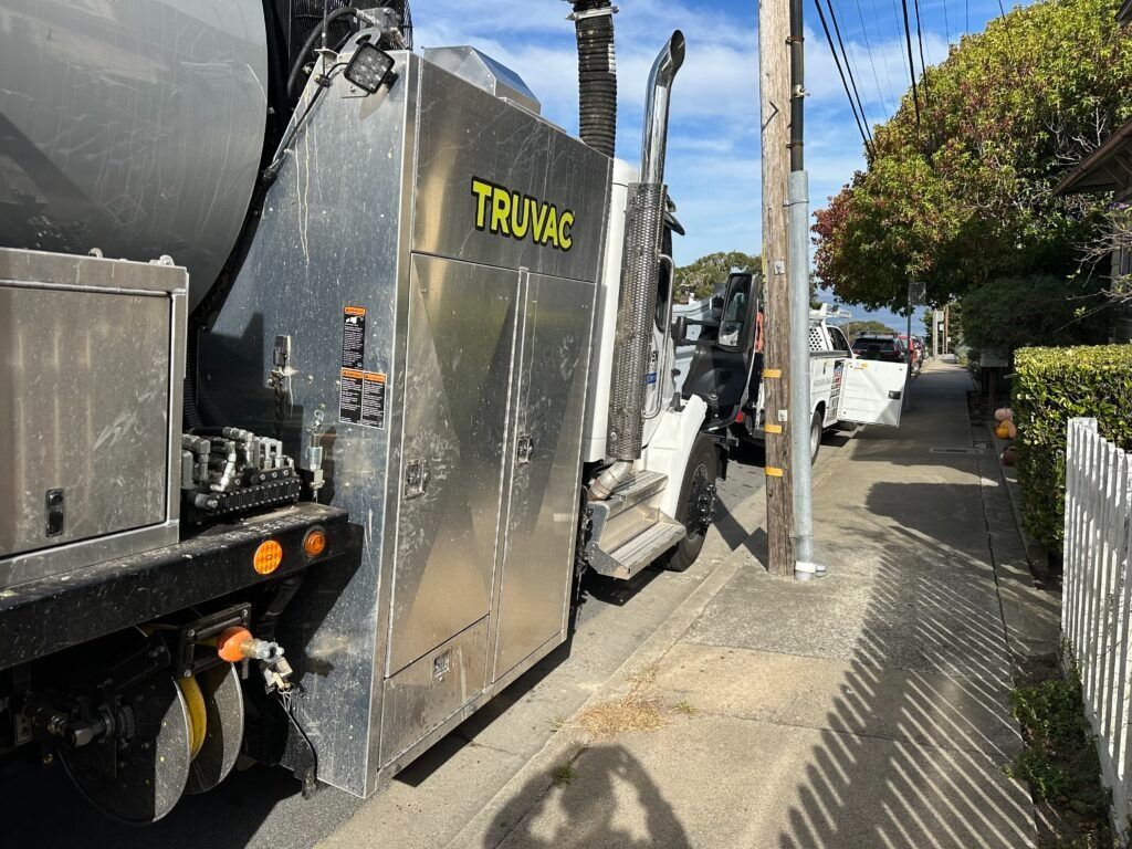A truck is parked on the side of the road next to a fence.