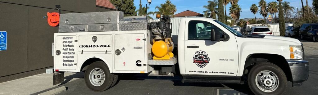 A white truck with a trailer attached to it is parked in a parking lot.
