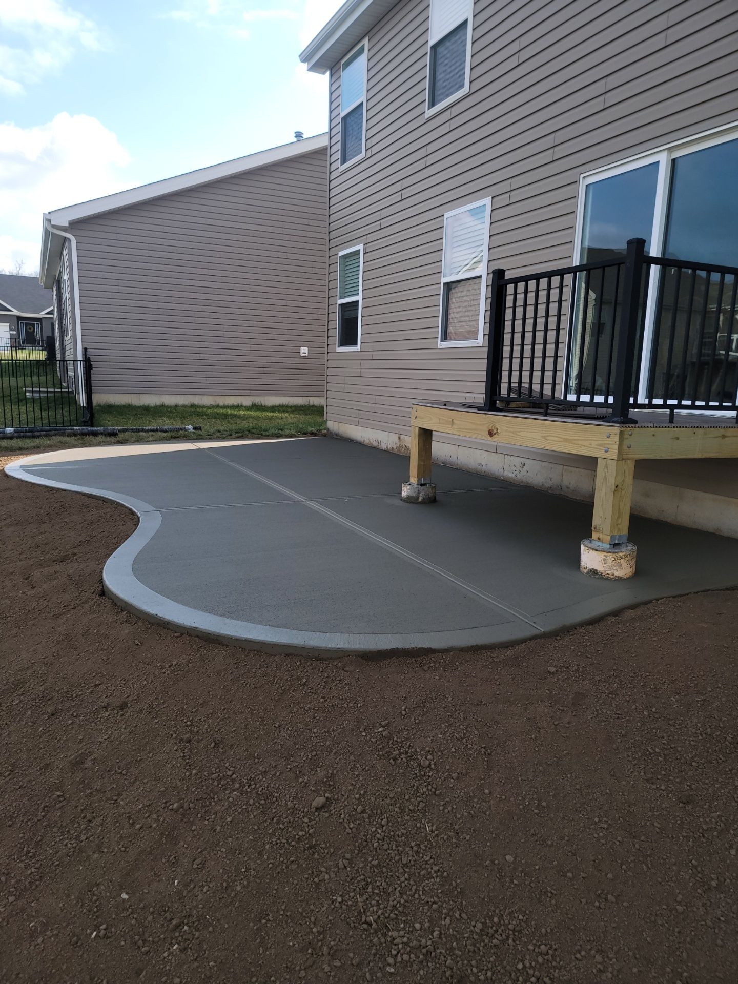 a patio with a deck and a house in the background .