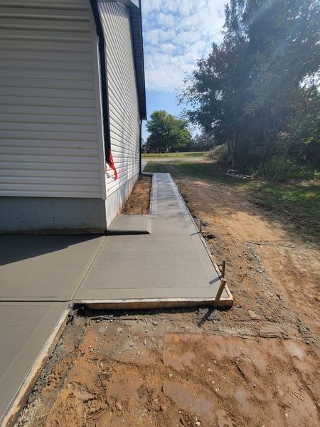 a concrete walkway is being built next to a house .