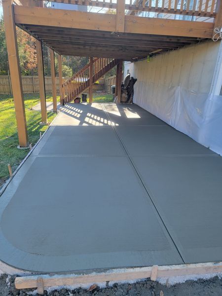 a concrete driveway under a wooden deck in a backyard .