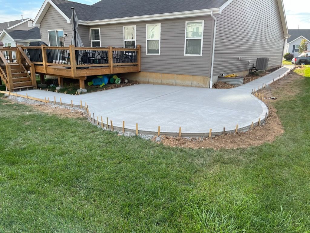 a concrete patio is being built in front of a house with a deck .