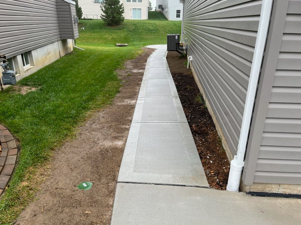 a sidewalk leading to a house next to a grassy field .
