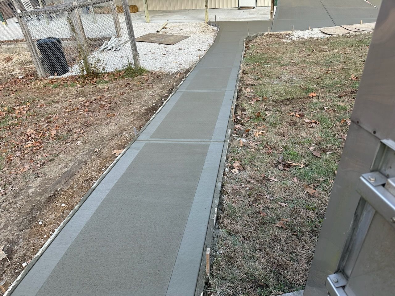 a concrete walkway with a fence in the background