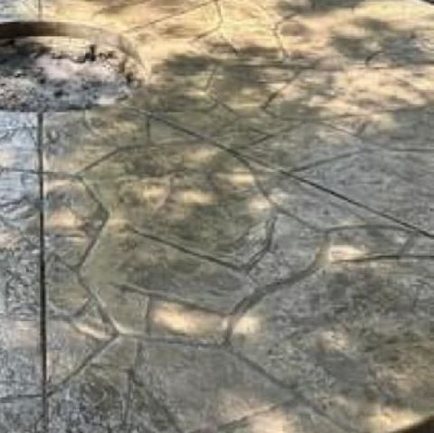 A close up of a concrete patio with a fire pit in the background.