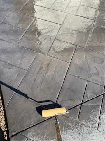 a roller is being used to paint a concrete floor .