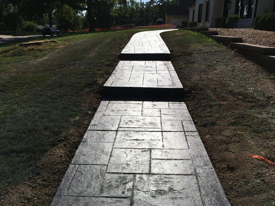 a concrete walkway with steps leading to a house .