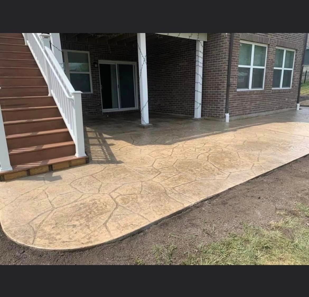 a concrete walkway leading to a brick house with stairs .