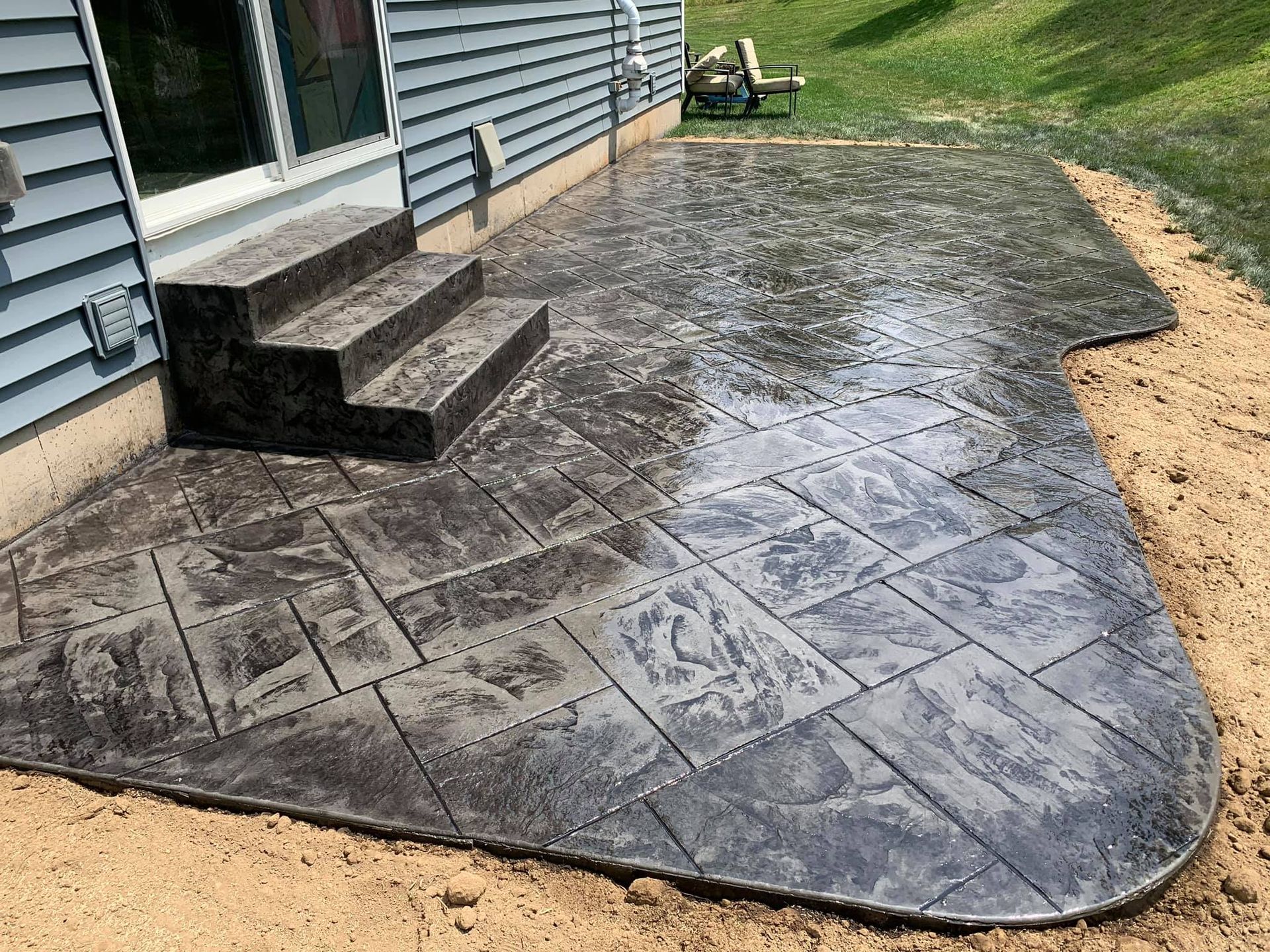 a concrete patio with stairs in front of a house .