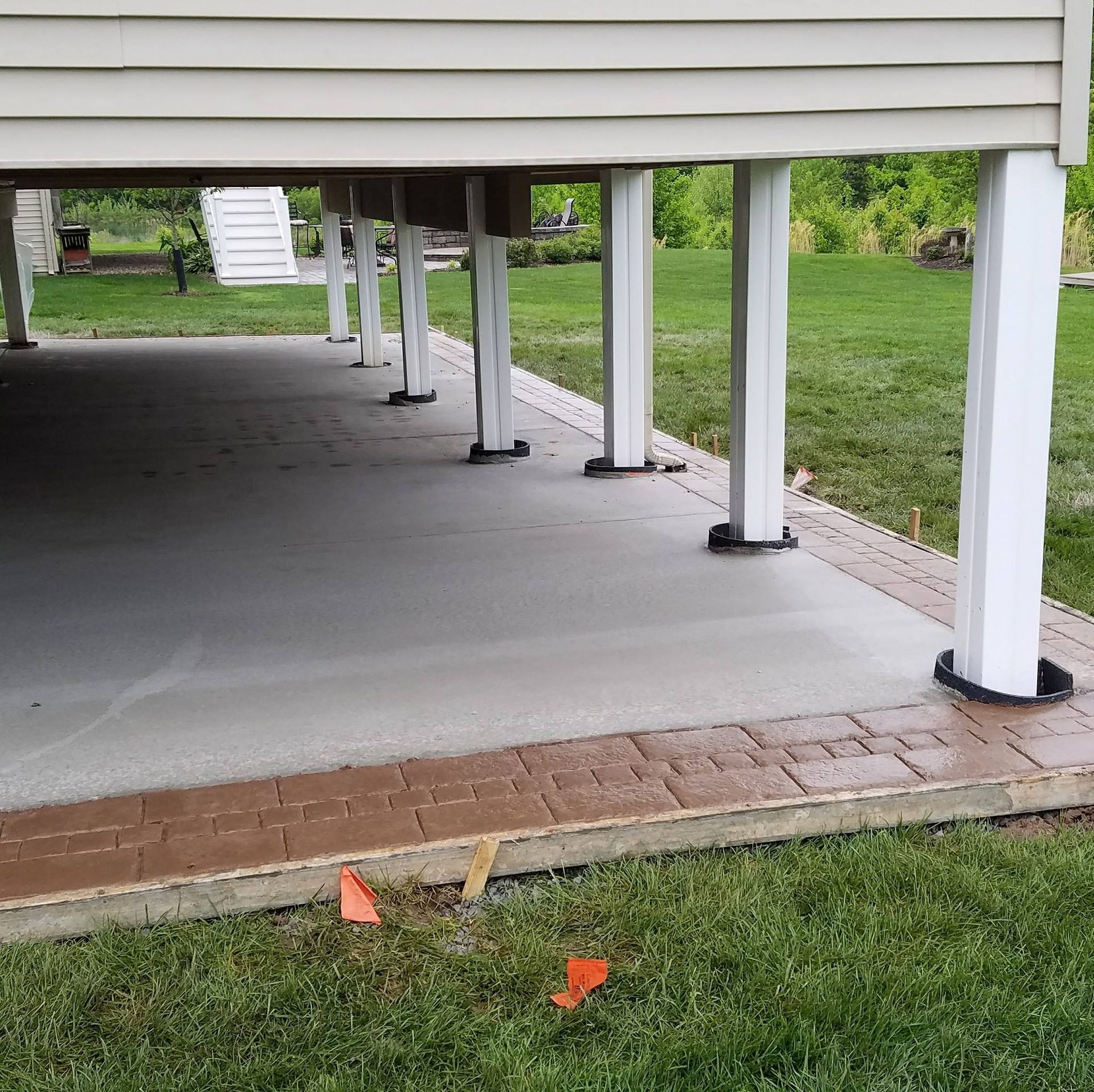 a concrete driveway under a house with a brick border
