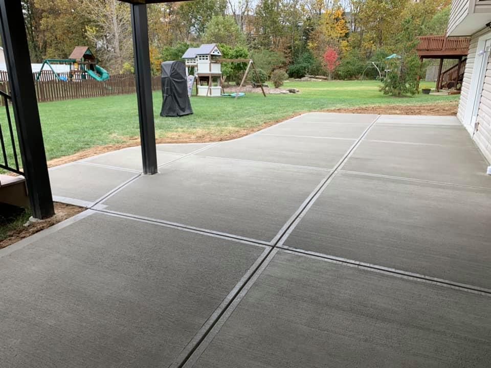 a large concrete patio with a swing set in the background .
