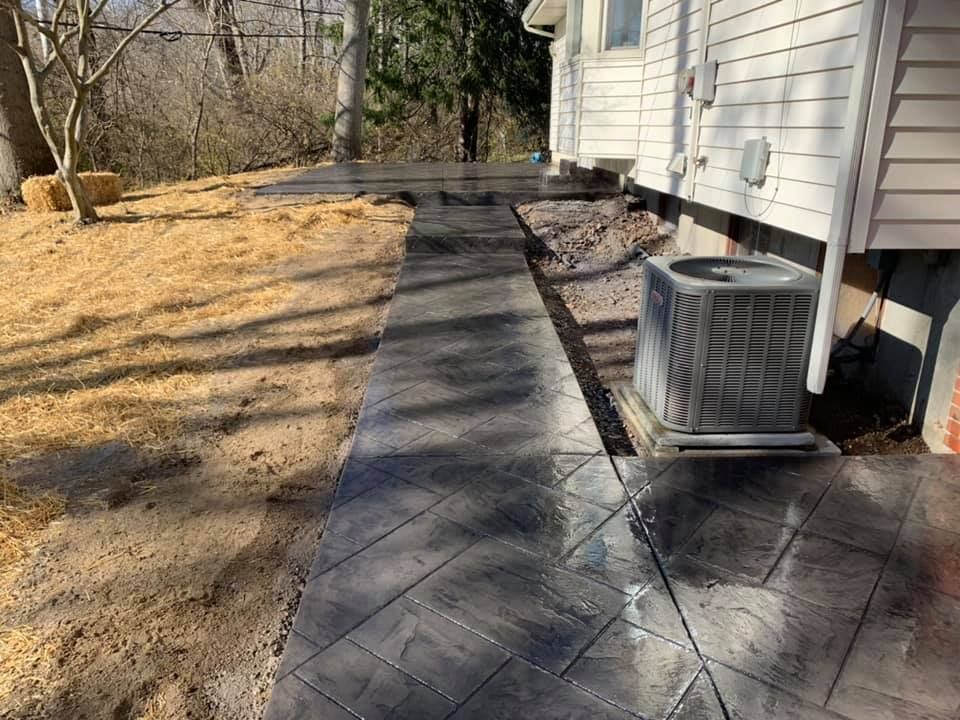 a walkway leading to a house with an air conditioner on the side of it .