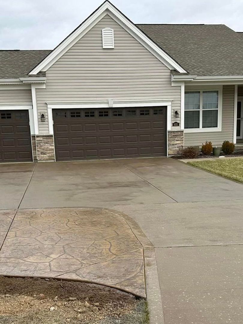 a house with two garage doors and a driveway in front of it .