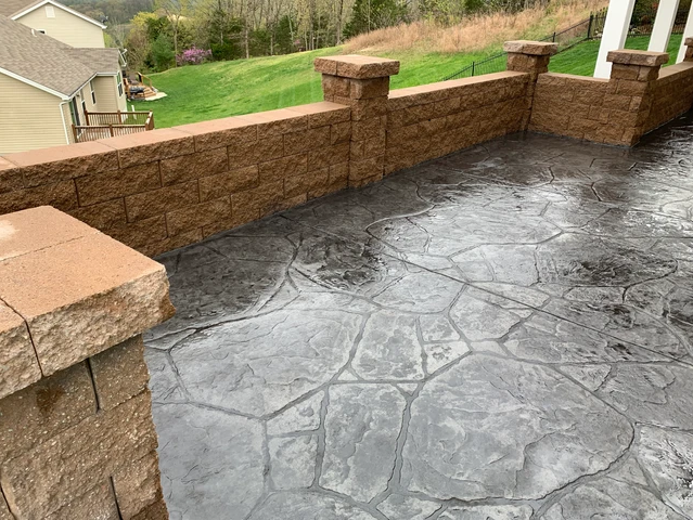 a patio with a brick wall and a concrete floor .