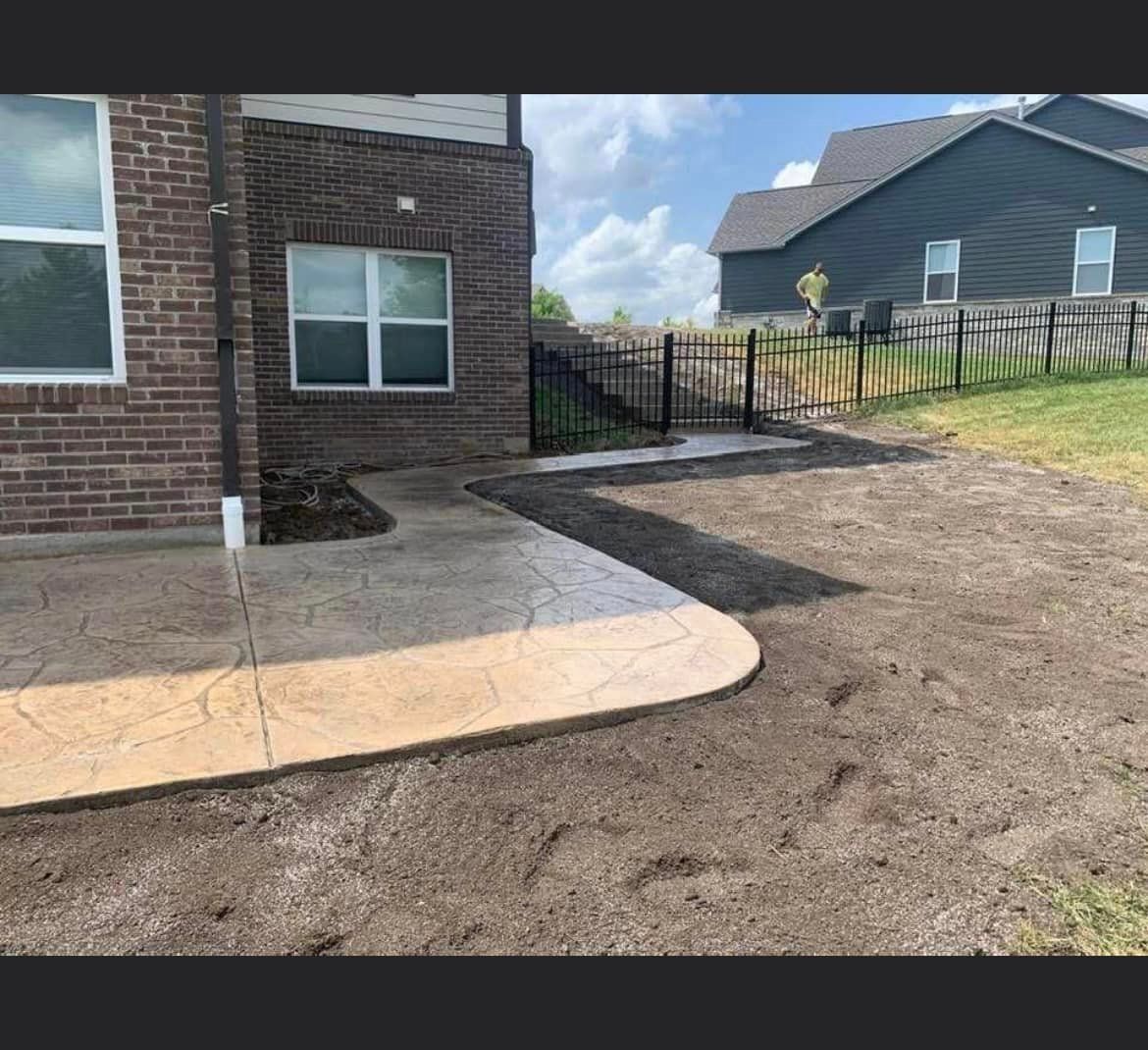 a brick house with a fence and a concrete walkway in front of it .