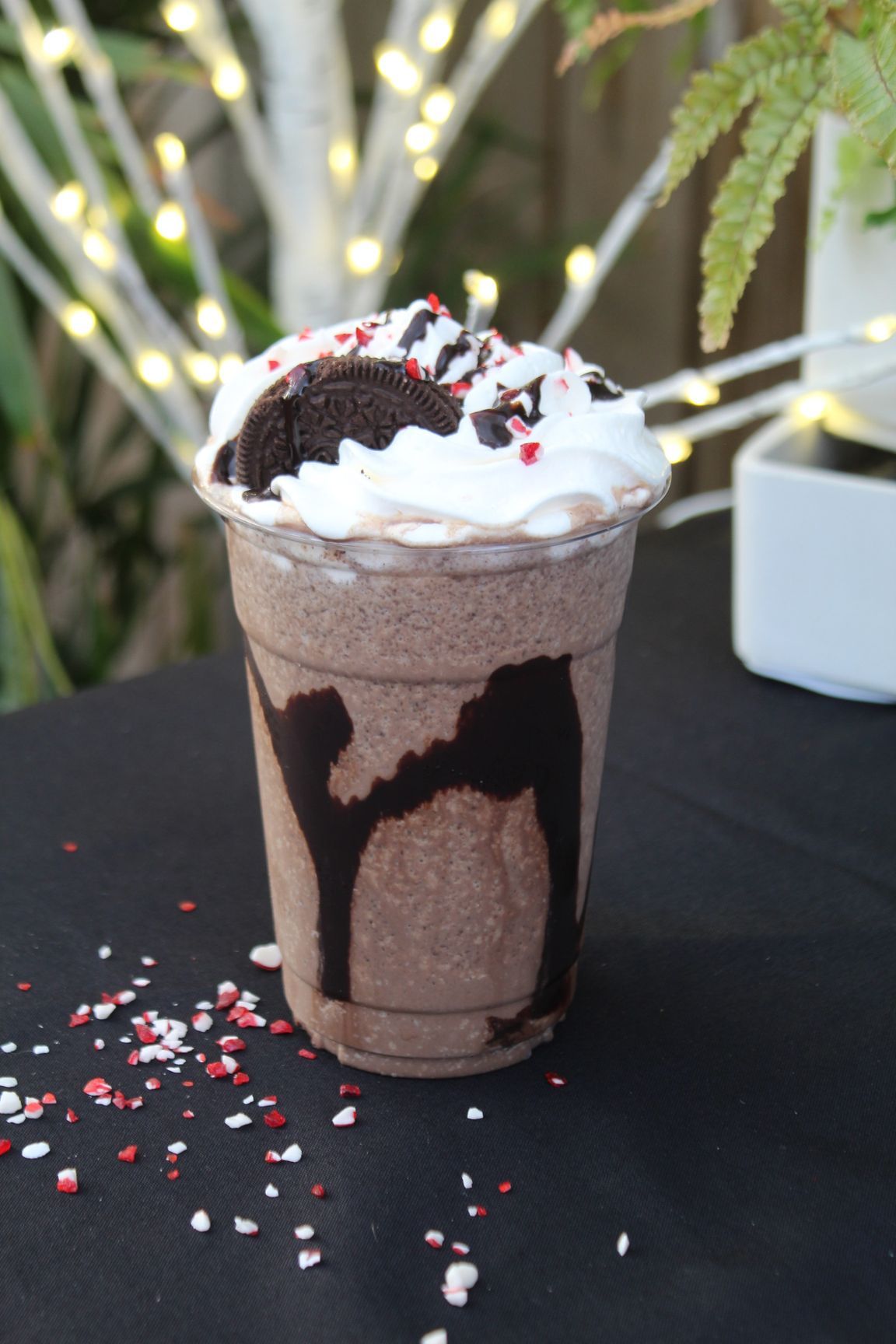 Iced coffee drink with cinnamon on top, next to pumpkins and yellow flowers on black.