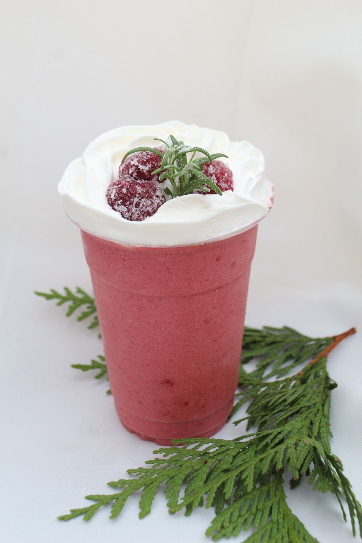Oreo milkshake in a clear cup with whipped cream, chocolate drizzle, straw, and cookie garnish.