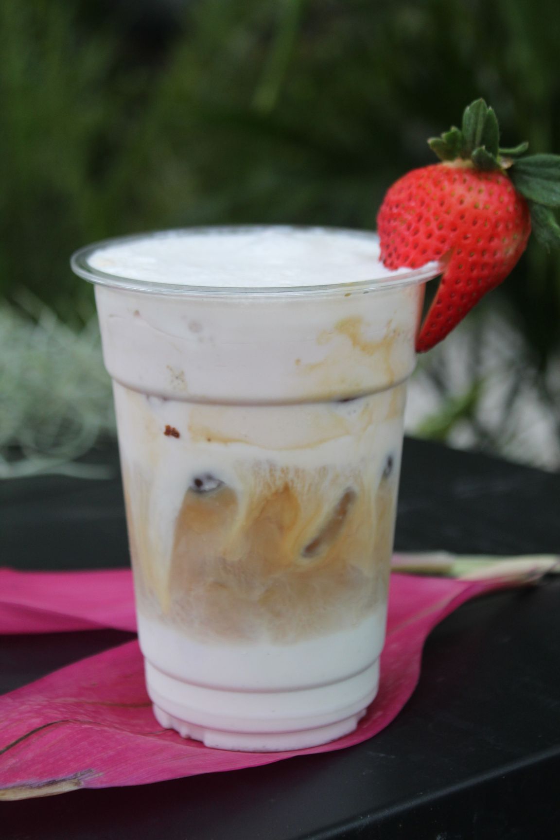 Oreo milkshake in a clear cup with whipped cream, chocolate drizzle, straw, and cookie garnish.
