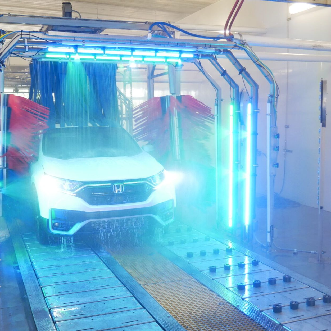 Red-lit car wash spraying a liquid over a car