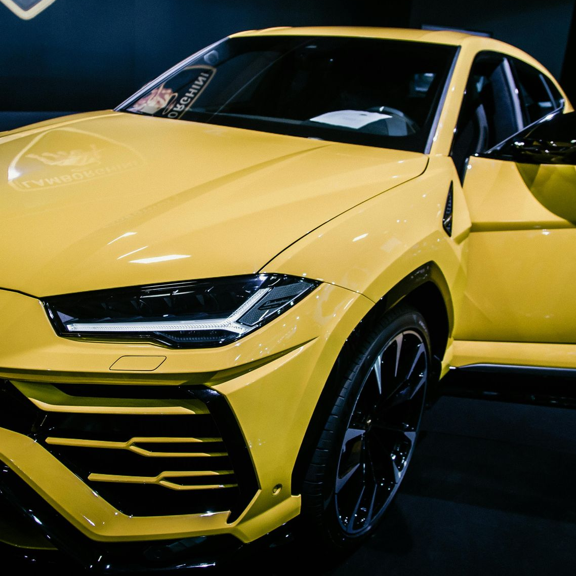 Yellow Lamborghini Urus SUV with black rims; door open.