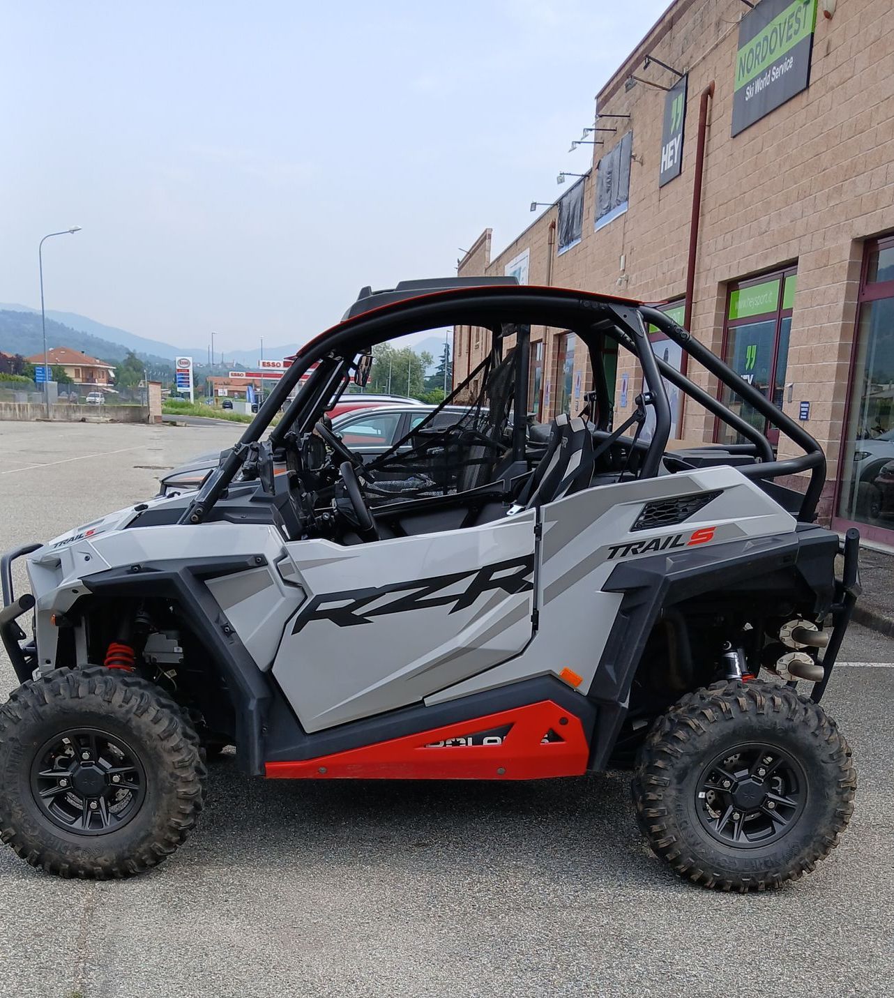 Polaris RZR grigia e rossa, parcheggiata fuori da un edificio.