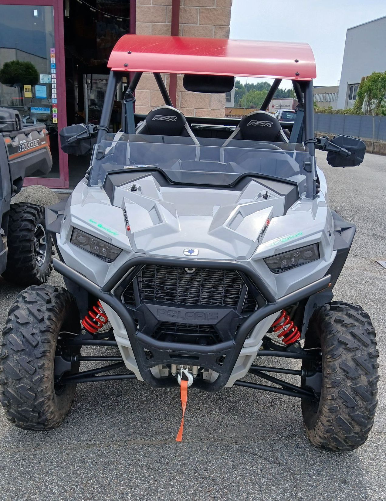 ATV affiancato grigio e rosso con roll-bar e pneumatici di grandi dimensioni parcheggiato all'esterno