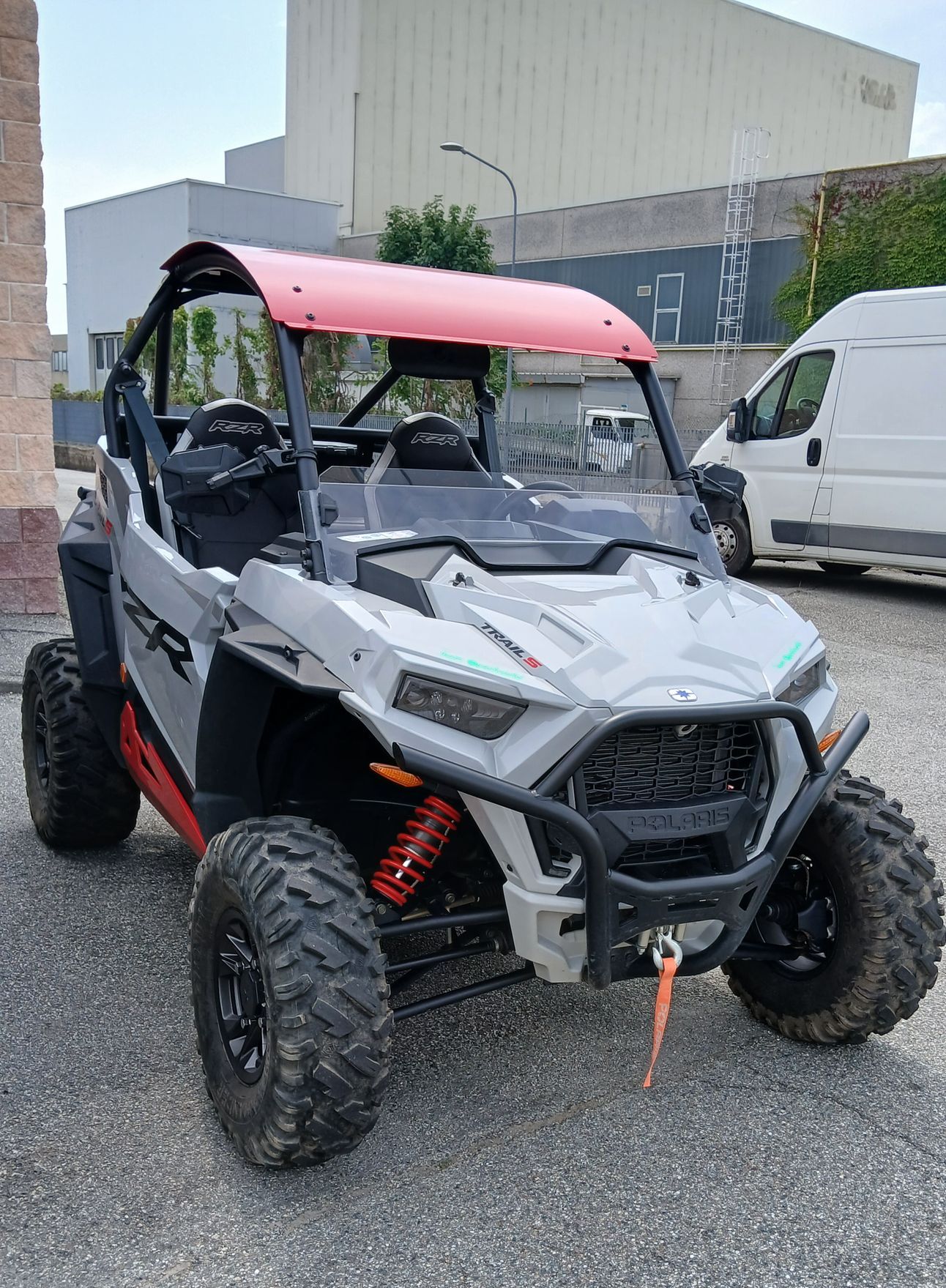 UTV Polaris RZR affiancati, grigio e rosso, parcheggiati all'aperto, con ruote nere e tetto rosso.