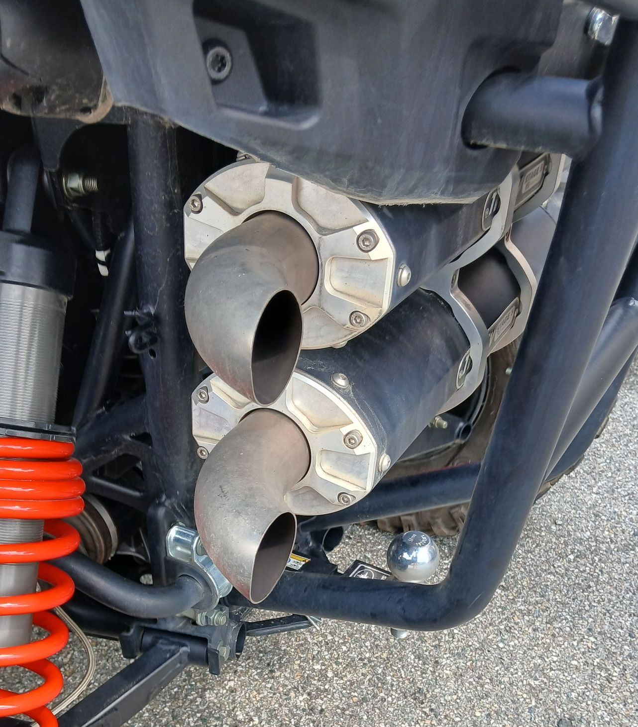 Doppi tubi di scarico su un telaio nero, sospensioni visibili e molle arancioni.