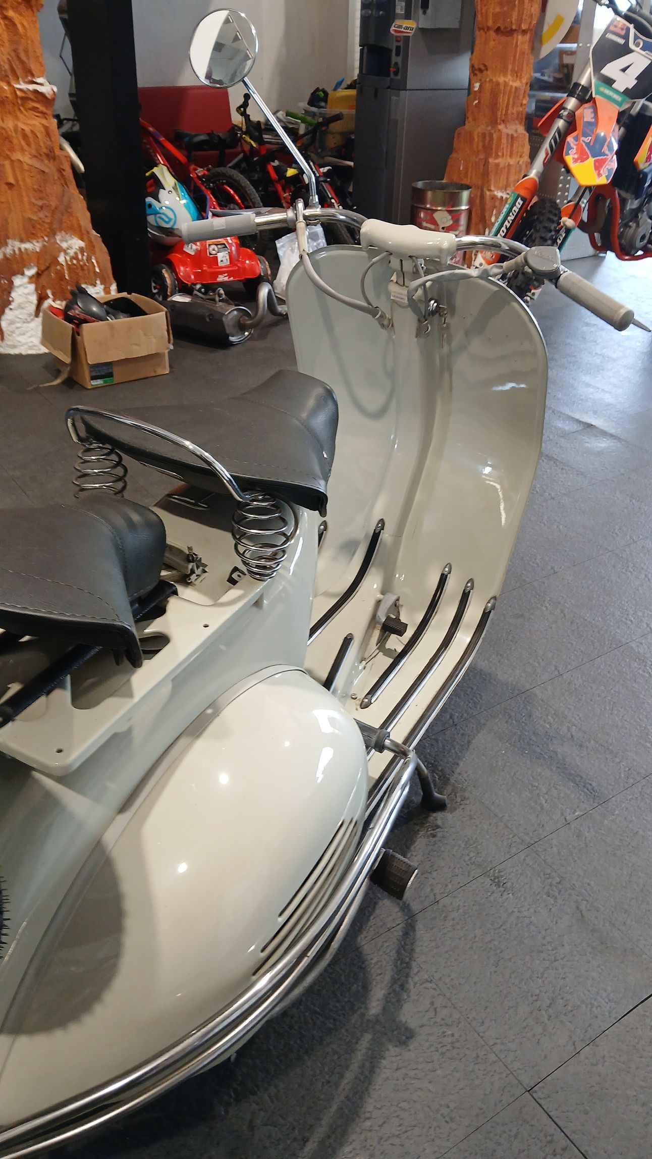 Scooter bianco d'epoca in un interno con uno sfondo di muro di mattoni.