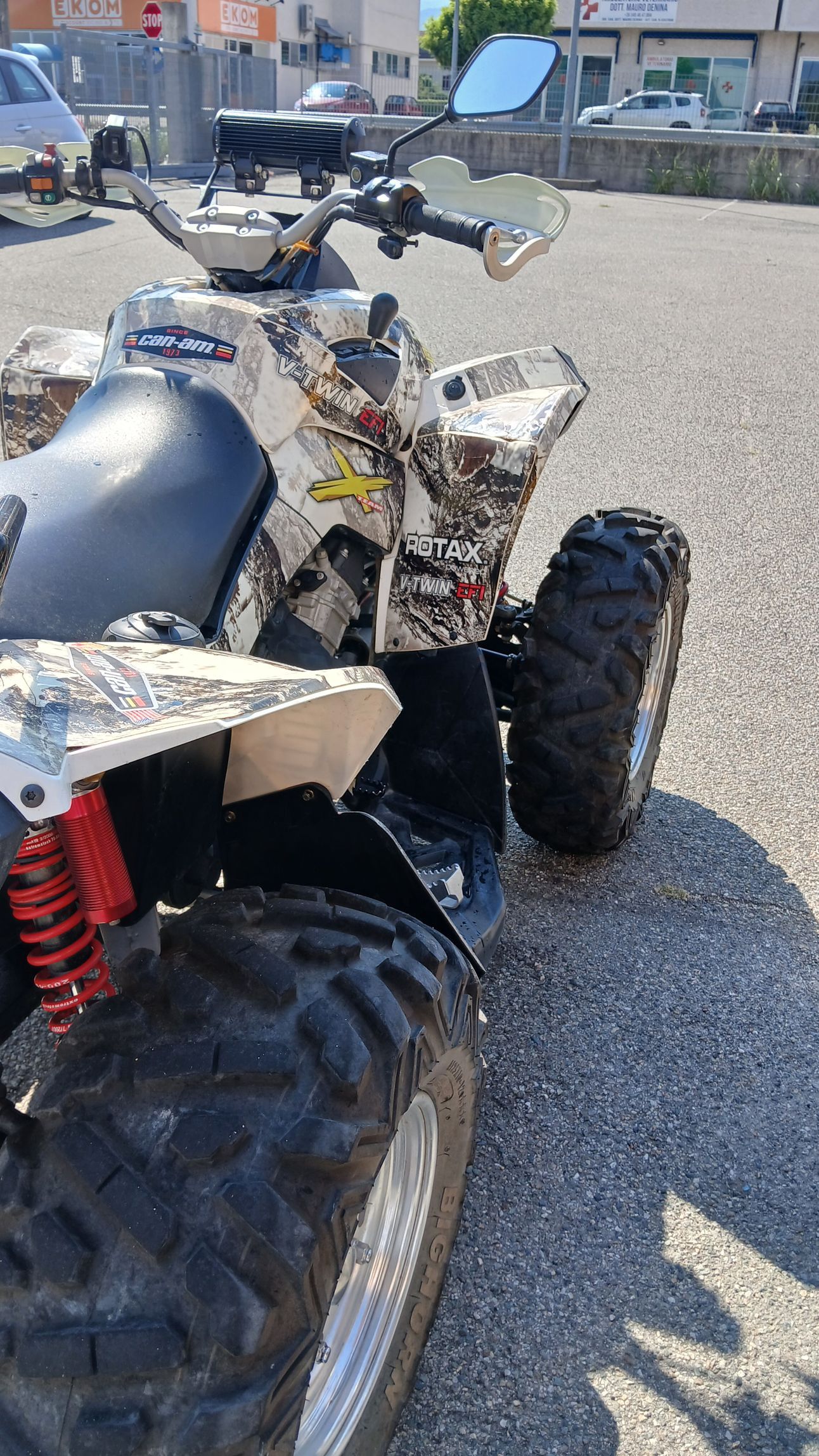 ATV bianco e mimetico parcheggiato sull'asfalto, primo piano della parte anteriore.