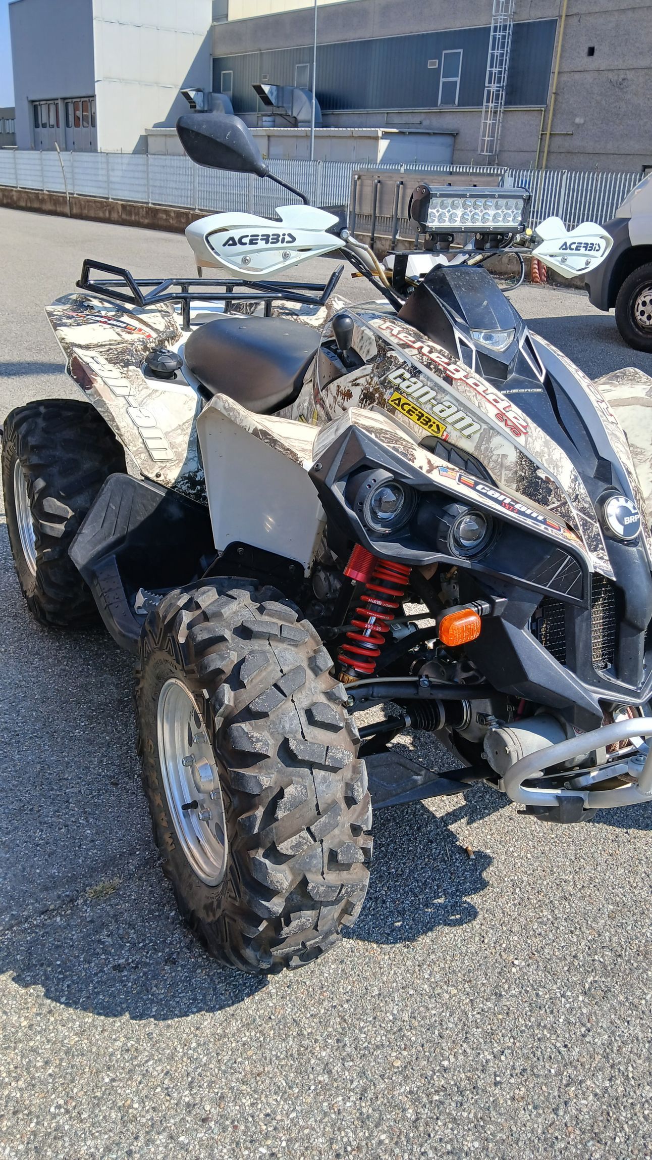 ATV mimetico parcheggiato sull'asfalto, vicino agli edifici.