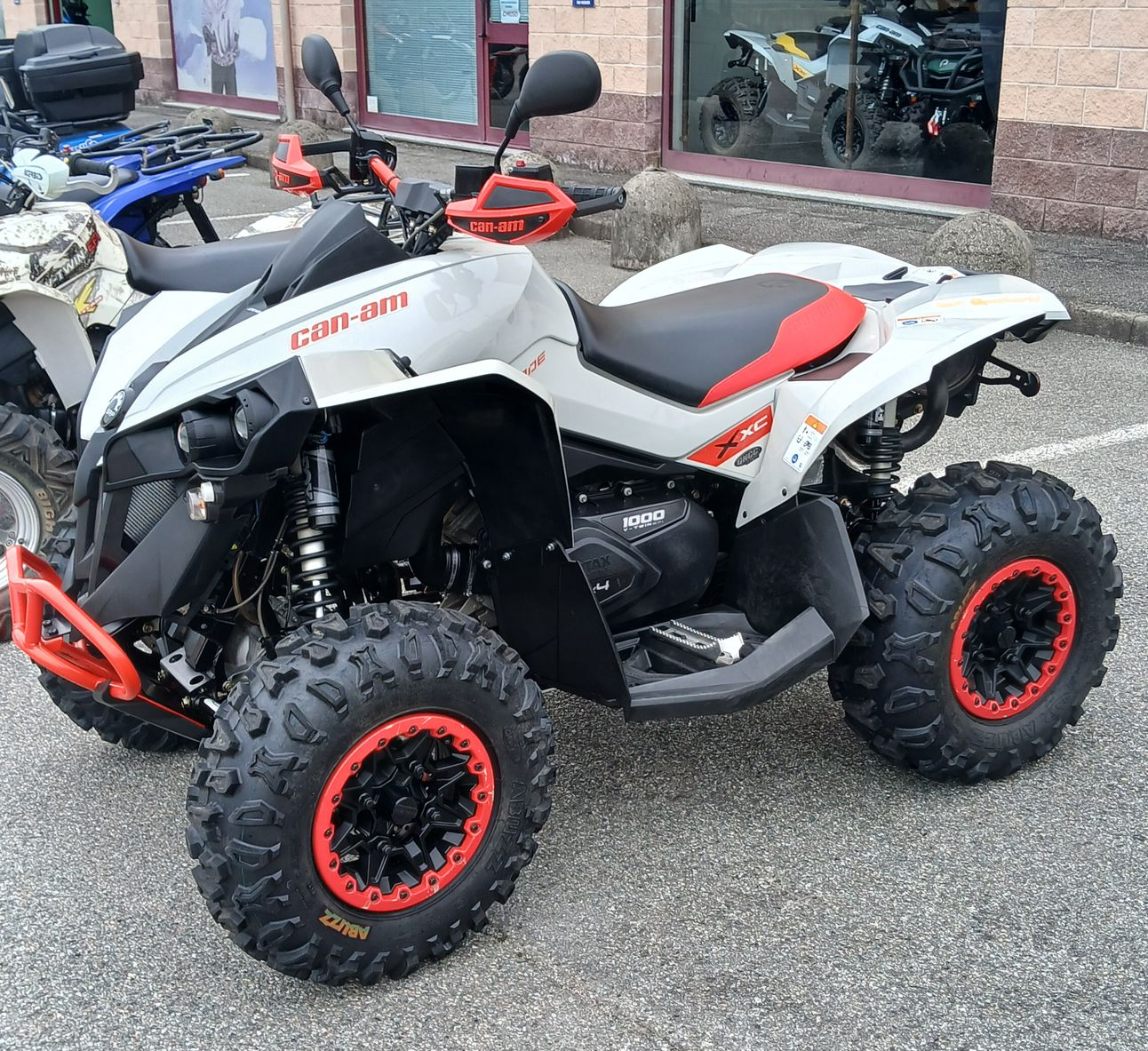 ATV Can-Am Renegade bianco e nero con dettagli arancioni, parcheggiato fuori da un edificio.