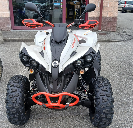Quad bianco e nero con dettagli arancioni, parcheggiato fuori da un edificio.