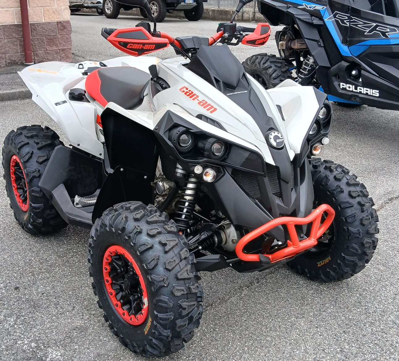 ATV Can-Am Renegade bianco e nero con dettagli rossi e grandi pneumatici tassellati, parcheggiato all'aperto.